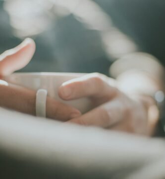 selective focus photography of person holding white mug